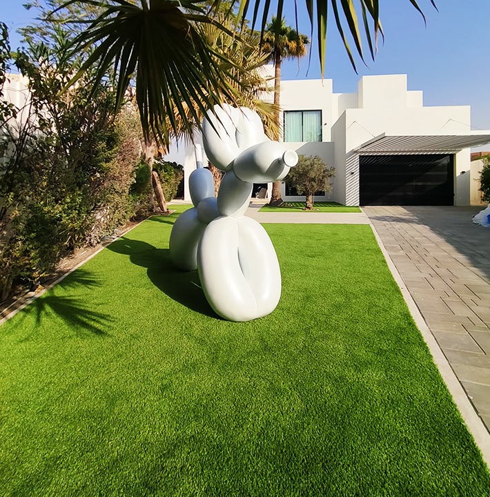 Artificial Grass Dubai Installation Creating A Vibrant Outdoor Space Featuring A Modern Sculpture As A Focal Point.